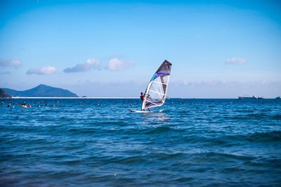 Man windsurfing in blue sea against sky on sunny day