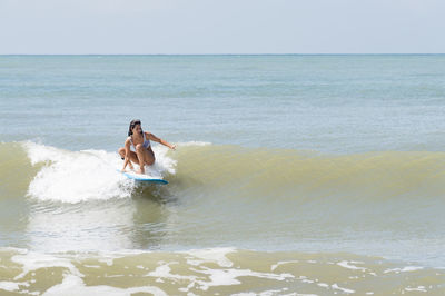 Young woman surfboarding in sea