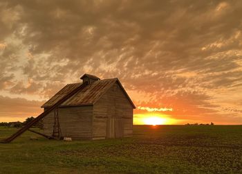 House on field against sky during sunset