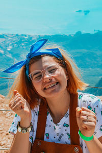 Portrait of smiling young woman holding sunglasses