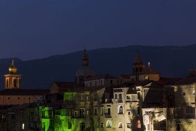 Illuminated buildings in city against clear sky at night