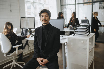 Portrait of businessman sitting with hands clasped sitting at office