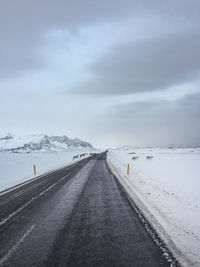 Road leading towards snow covered mountain against sky