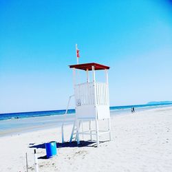 Lifeguard hut on beach against clear blue sky