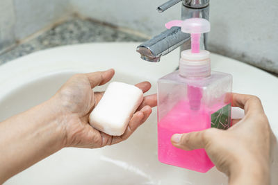 Cropped hand washing hands in sink