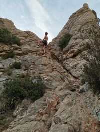 Low angle view of person on rock formation against sky