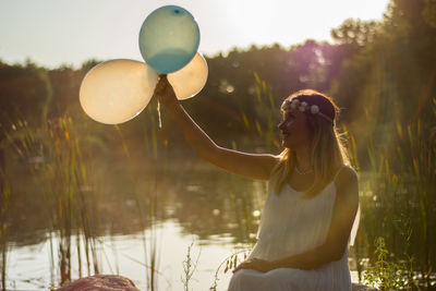 Close-up of woman holding balloons against trees