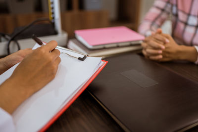 Midsection of woman writing in book