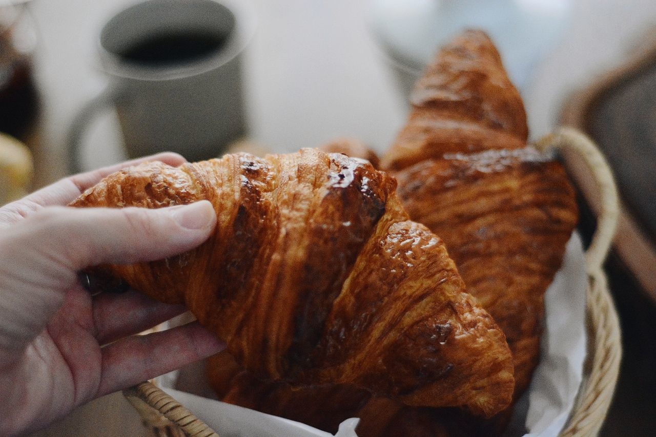 food and drink, food, hand, croissant, freshness, one person, baked, meal, dessert, bread, french food, dish, indoors, close-up, breakfast, holding, fast food, viennoiserie, pastry, cuisine, lifestyles
