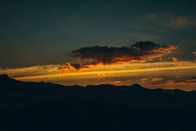 Scenic view of silhouette mountain against dramatic sky during sunset