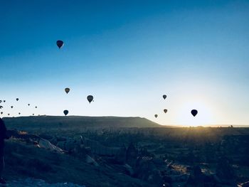 Hot air balloons flying over landscape against clear sky