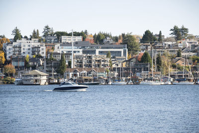 Sailboats in sea against buildings in city