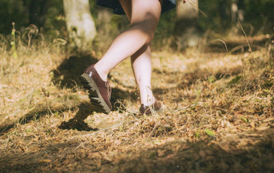 Low section of woman walking on field