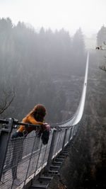 Rear view of woman walking on railing against trees