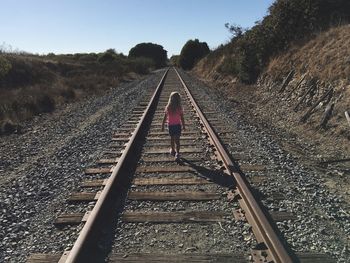 Rear view full length of girl walking on railroad track