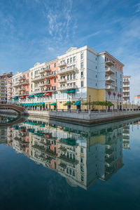 Buildings by river in city against sky