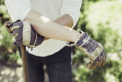 Midsection of man wearing gardening gloves at yard