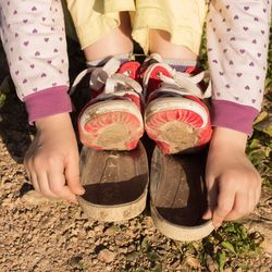 Low section of child showing damaged shoes on sunny day