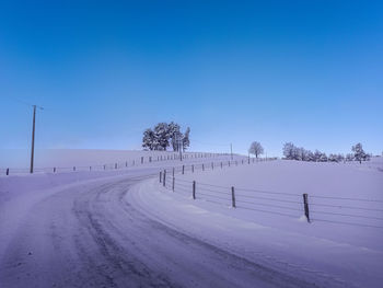 Scenic view of snow covered landscape against clear blue sky