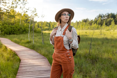 Woman botanist with backpack on ecological hiking trail. naturalist exploring wildlife, ecotourism.