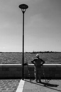 Rear view of man standing by sea against clear sky