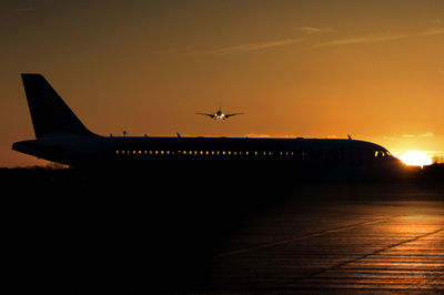 Silhouette airplane flying against sky during sunset