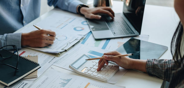 Midsection of business people working on table