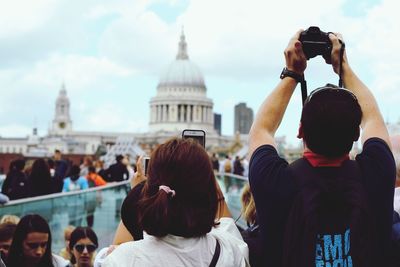 Rear view of people photographing against sky