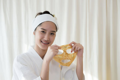 Young woman removing facial mask from face in spa