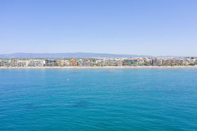 Scenic view of sea and buildings against clear blue sky