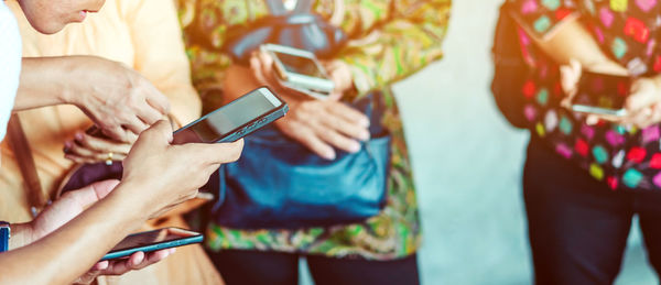 Close-up of friends using mobile phones in home