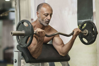 Shirtless man lifting weights in gym