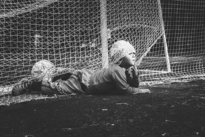 Playful boy lying on playing field in soccer goal
