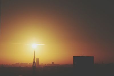 Distant view of eiffel tower in city against sky during sunset