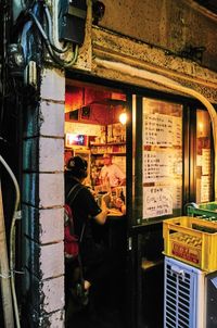 Midsection of woman standing by illuminated store at night