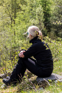 Woman sitting on rock in forest