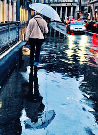 Rear view of person walking on wet street during monsoon