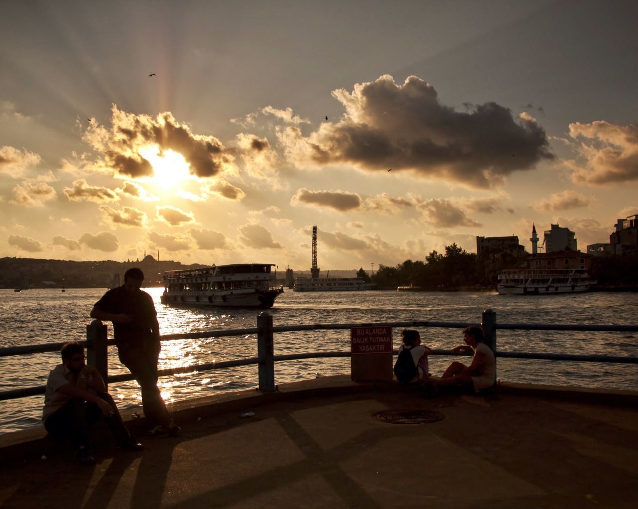 sunset, sun, water, sky, silhouette, sea, cloud - sky, sunlight, sunbeam, lifestyles, transportation, men, leisure activity, person, mode of transport, lens flare, sitting, nature