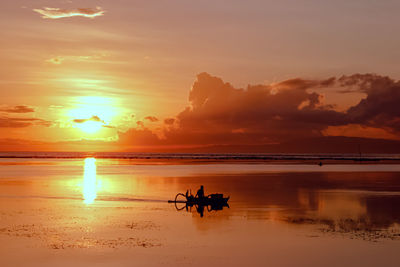 Silhouette people on beach against sky during sunset