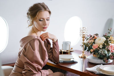 Beautiful woman in private jet in stylish dress with hairstyle and make-up sits