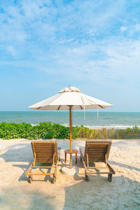 Chairs and lounge chair at beach against sky