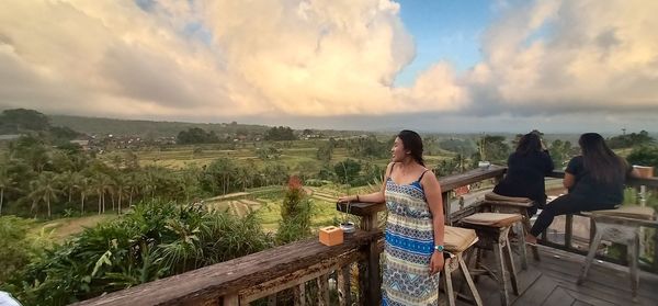 Woman standing by railing against sky