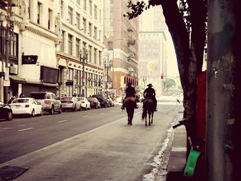 Rear view of people walking on road amidst buildings