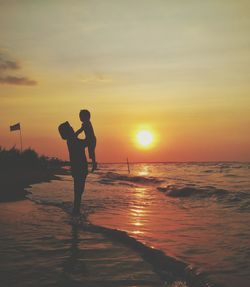 Silhouette man standing on beach against sky during sunset