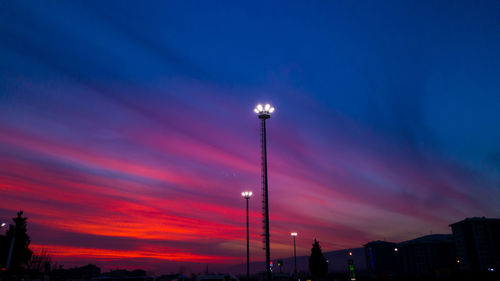 Illuminated city against sky at sunset