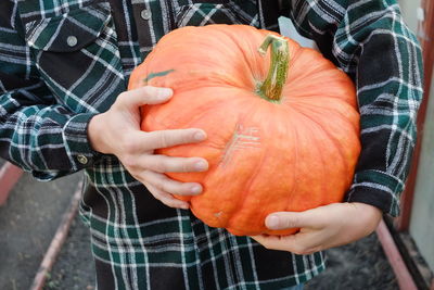 Midsection of man holding pumpkin