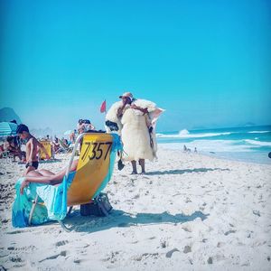 People at beach against clear sky