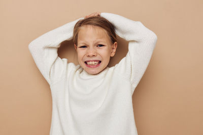 Portrait of girl standing against beige background