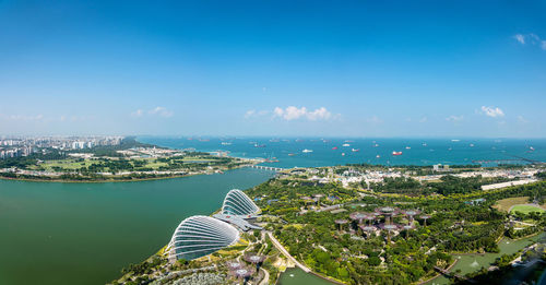 High angle view of city by sea against blue sky