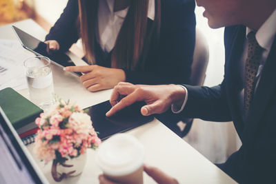 Midsection of business people using digital tablet in office